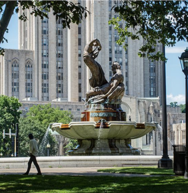 Person walking in front of Frick Fine Arts fountain